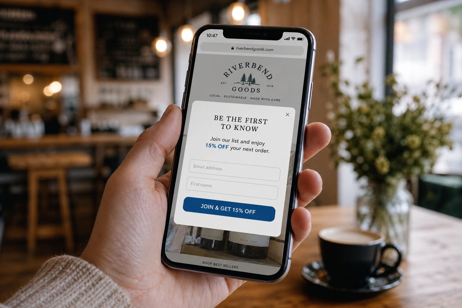 A hand holding a phone showing a website pop-up offering a discount to join the email list.